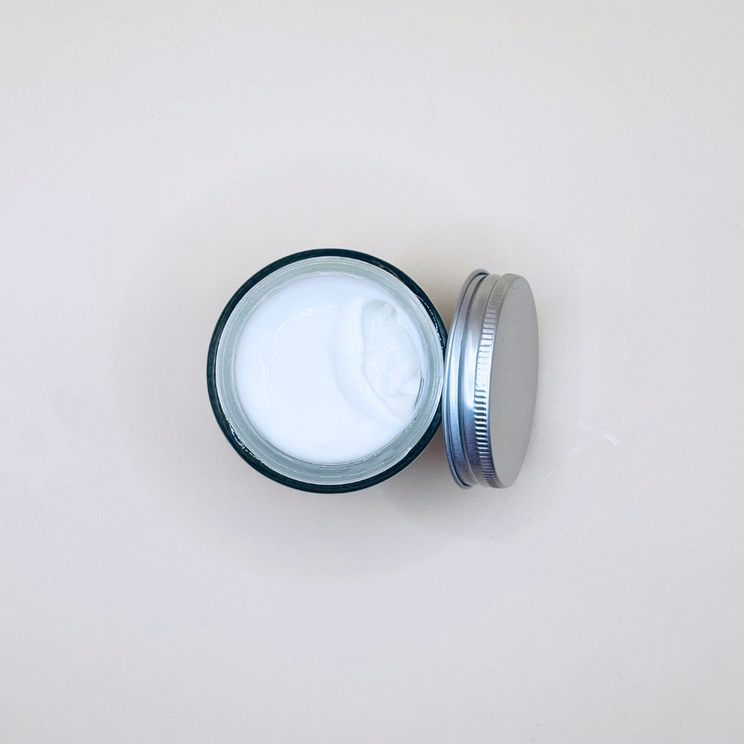 Open jar of white cream on a light beige background