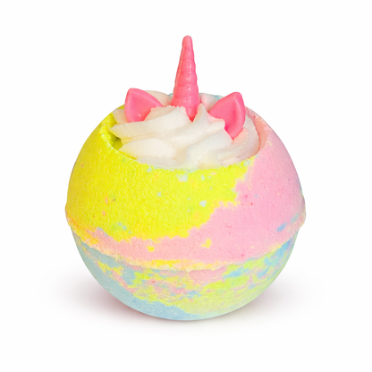 A pastel multicoloured bath bomb with white whipped bubble bath frosting on top, with unicorn ears and a horn shaped soap on top, on a white background.
