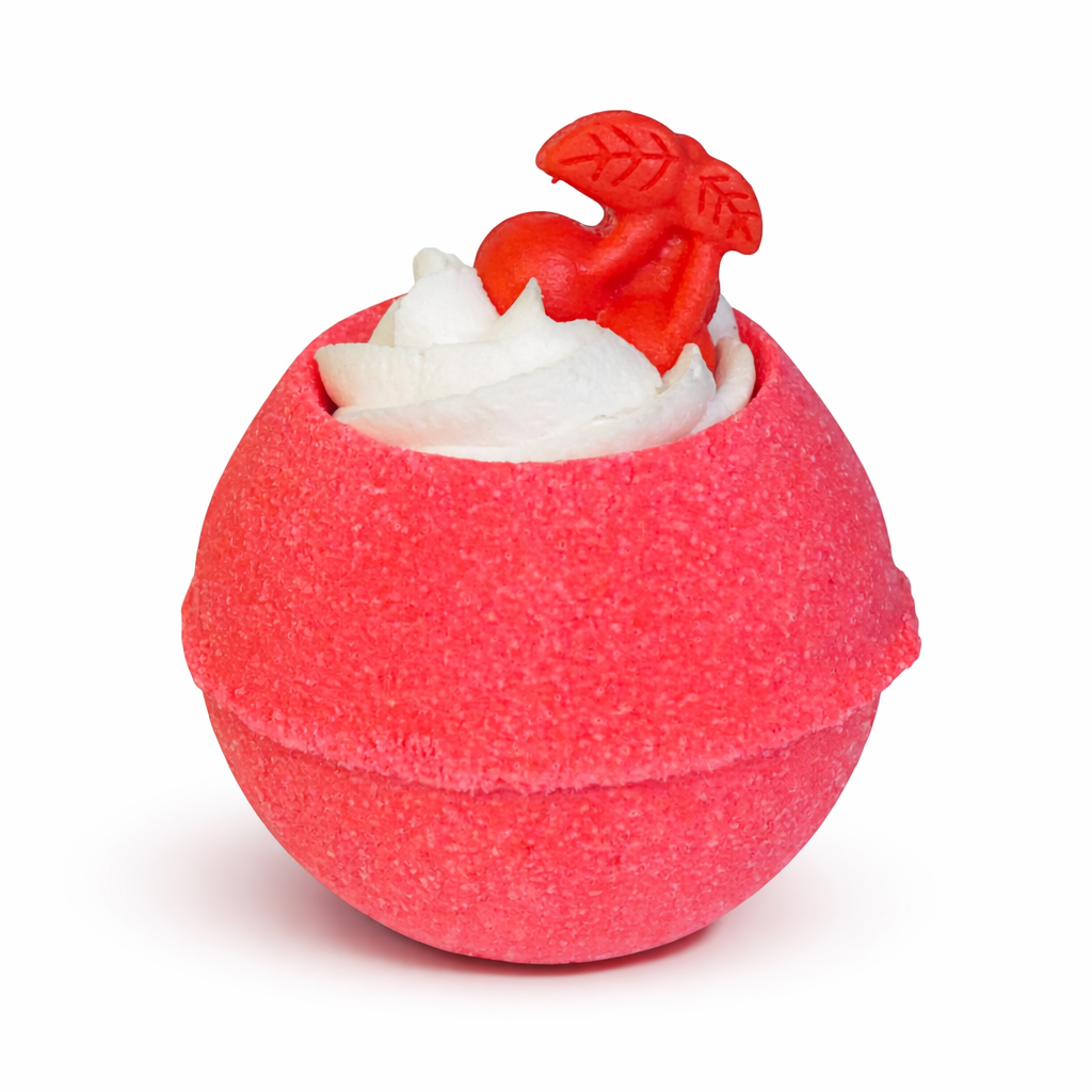 A red round bath bomb with a white whipped bubble bath frosting on top with a cherry shaped soap on top, on a white background.